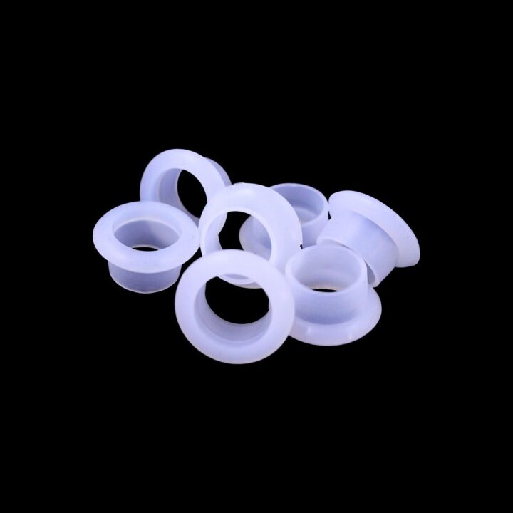 A group of white plastic eyelets on top of a black background.